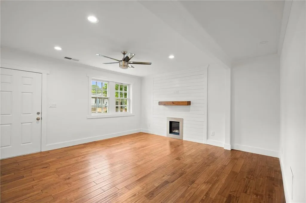 Unfurnished living room featuring a ceiling fan, a fireplace, wood finished floors, and recessed lighting
