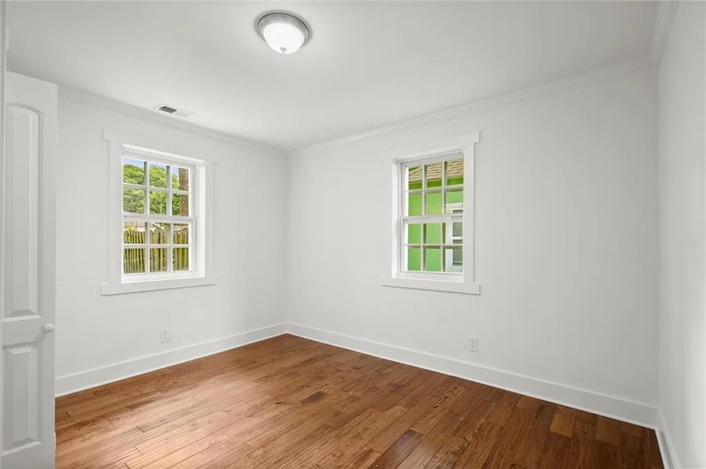 Spare room with wood-type flooring and ornamental molding
