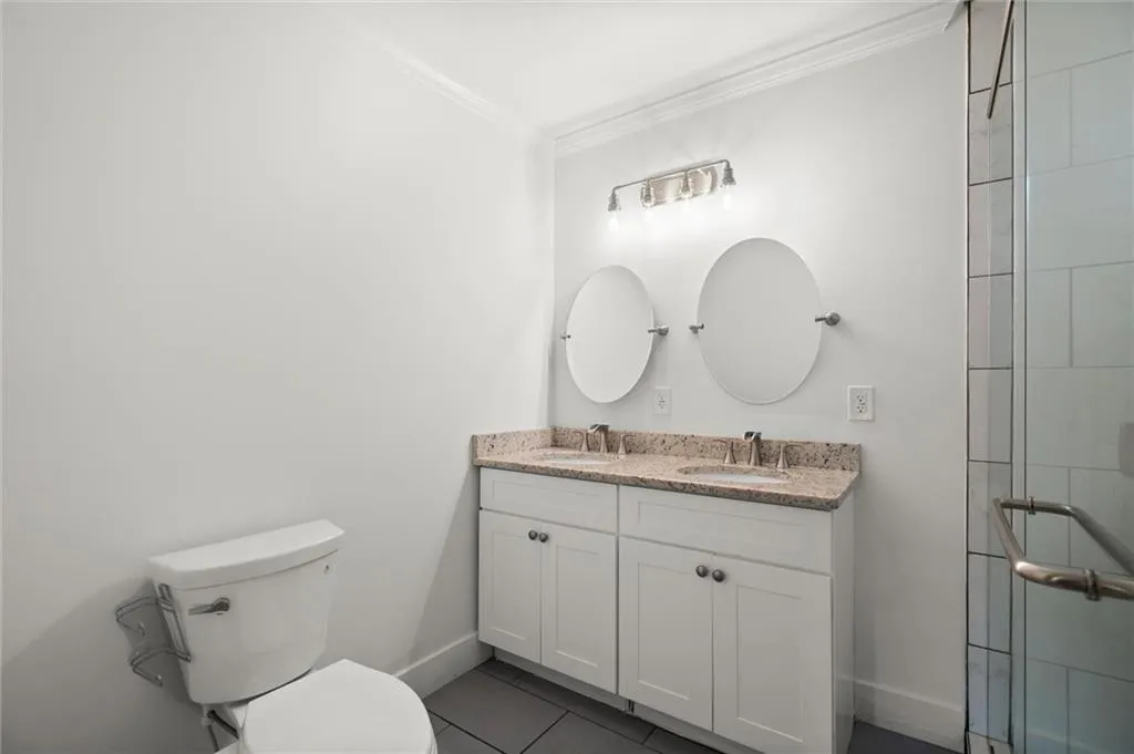 Bathroom featuring ornamental molding, double vanity, a tile shower, and tile patterned floors