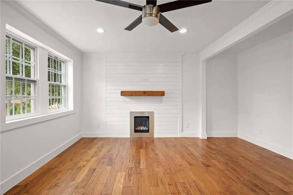 Unfurnished living room with hardwood / wood-style floors, plenty of natural light, a large fireplace, ornamental molding, and recessed lighting