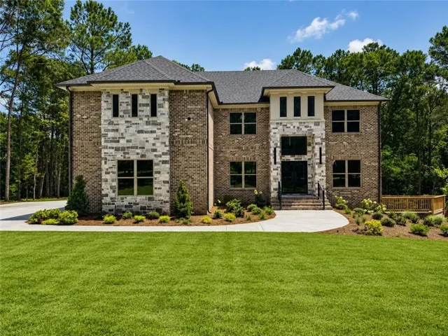 Stately two-story brick and stone facade residence featuring a prominent entry with stone steps and iron railings