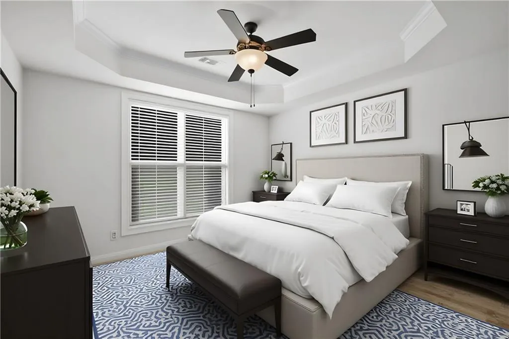 Bedroom featuring ornamental molding, wood finished floors, ceiling fan, and a raised ceiling