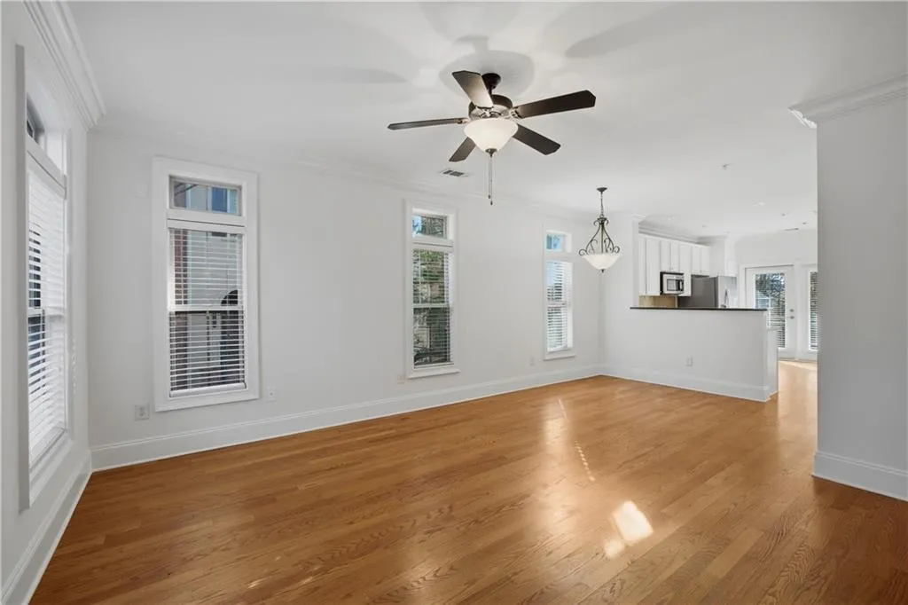 Unfurnished living room featuring ornamental molding, ceiling fan, and light wood-style flooring