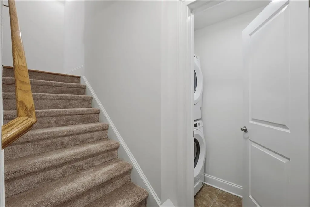Laundry room with stacked washer and dryer and baseboards