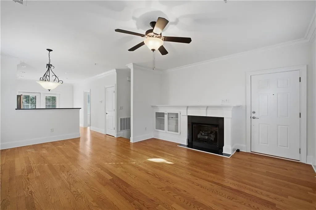Unfurnished living room featuring a fireplace, light wood-style flooring, a ceiling fan, and crown molding