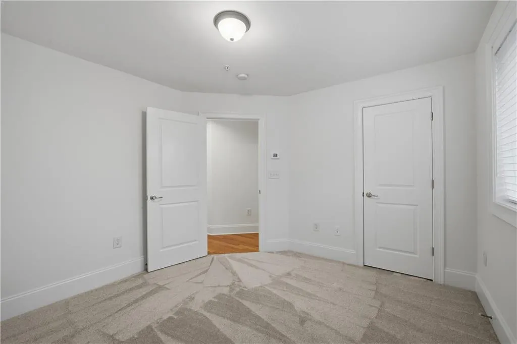 Unfurnished bedroom featuring light carpet and baseboards