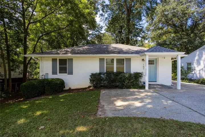 White brick exterior featuring a light blue entry door, covered porch, and mature landscaping