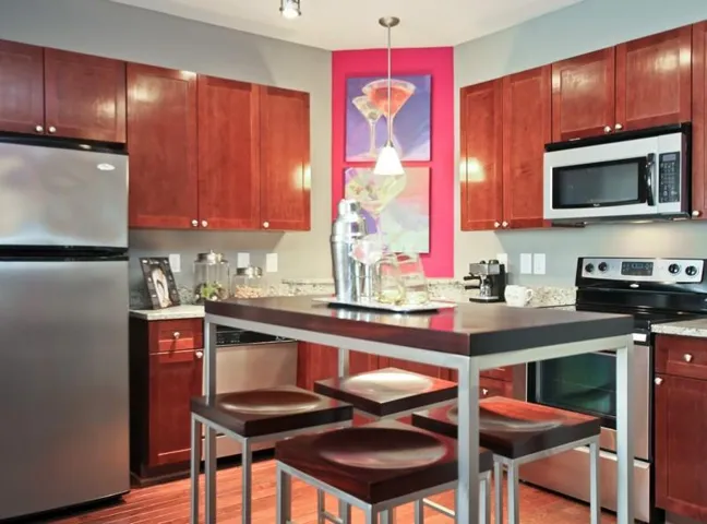 Kitchen with hardwood / wood-style floors, pendant lighting, and appliances with stainless steel finishes
