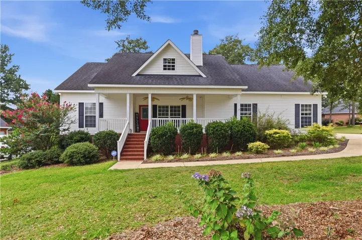 White siding exterior with a dark shingle roof, covered front porch, and a visible chimney