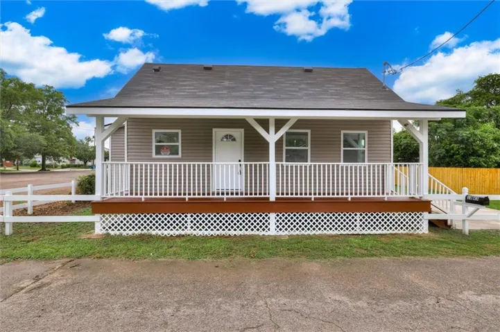 Welcoming front porch featuring a rich brown deck, white railing, and decorative lattice skirting