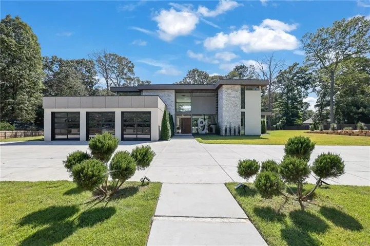 Contemporary exterior with stone veneer accents, expansive glass panels, a three-car garage with frosted glass doors, and a concrete driveway