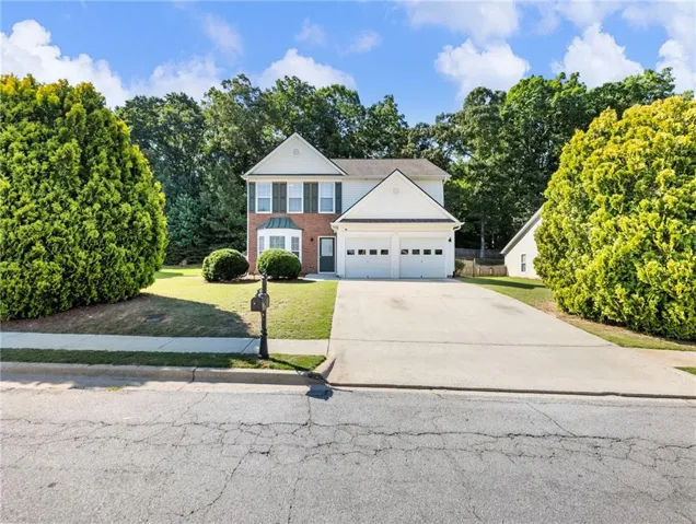 Two-story residence featuring a brick and siding exterior, a two-car garage, and a concrete driveway