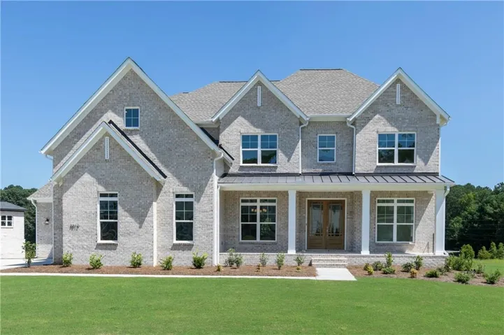 Contemporary brick exterior with a prominent covered porch, double entry doors, multiple gable roofs, and a manicured lawn