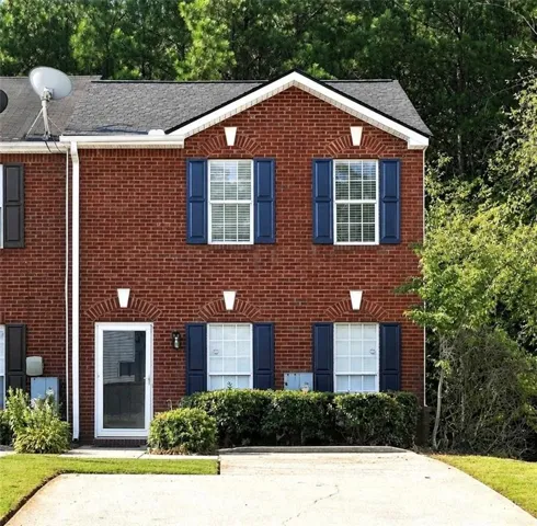 Brick exterior with navy blue shutters, white window trim, and a gabled roofline