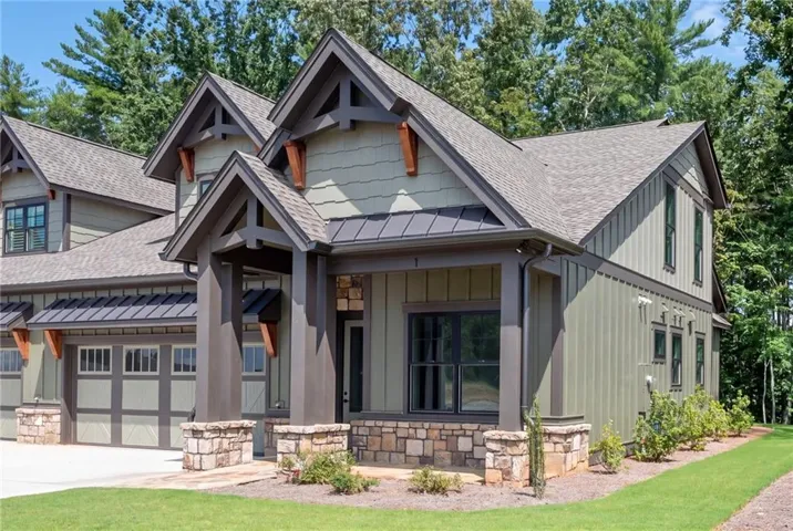 Craftsman-style exterior with a covered entry, stone accents, horizontal and vertical siding, and a two-car garage