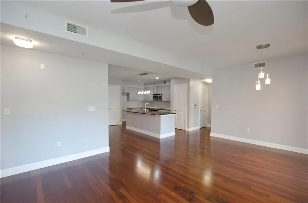 Unfurnished living room featuring ceiling fan and dark wood-style flooring