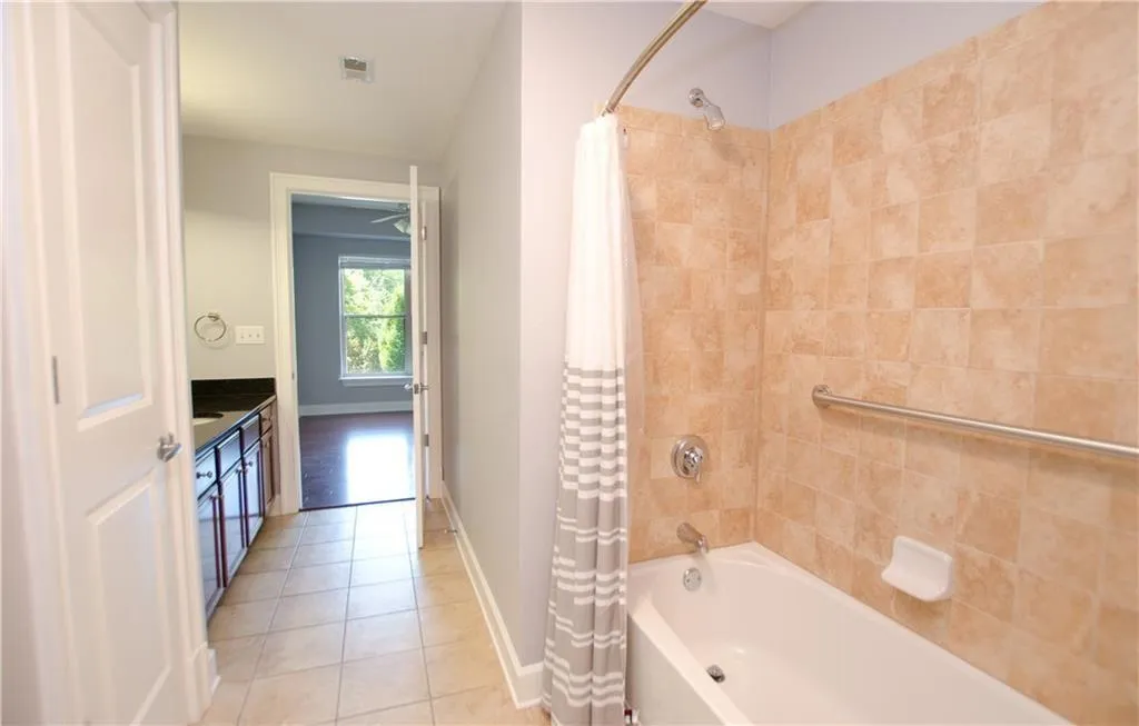 Bathroom featuring shower / tub combo with curtain, tile patterned floors, and vanity
