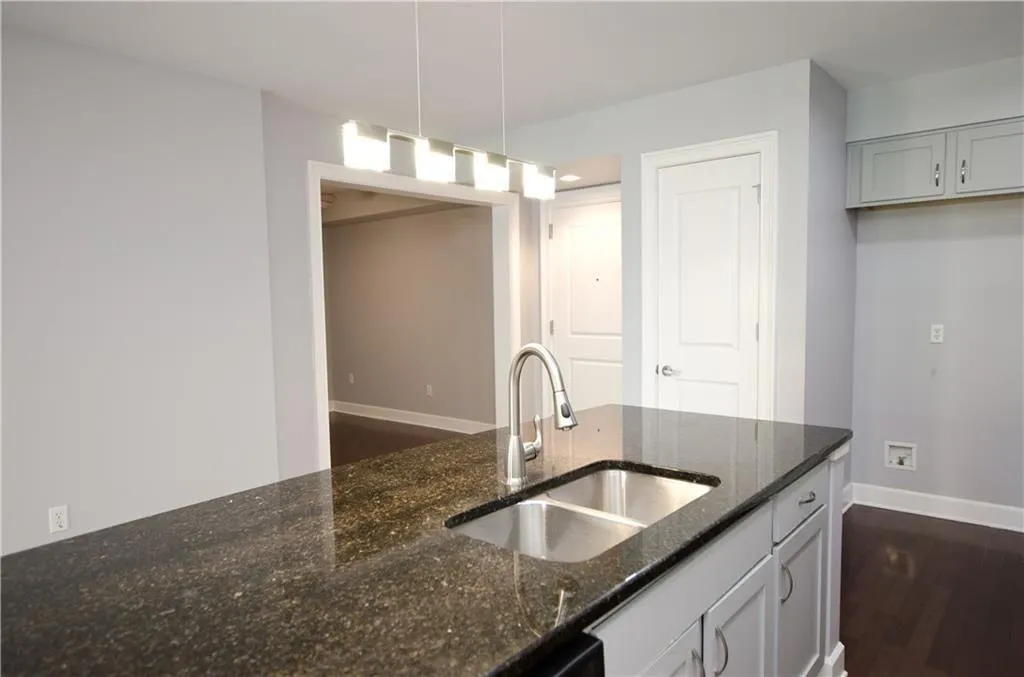 Kitchen featuring dark stone countertops, hanging light fixtures, and dark wood-style floors