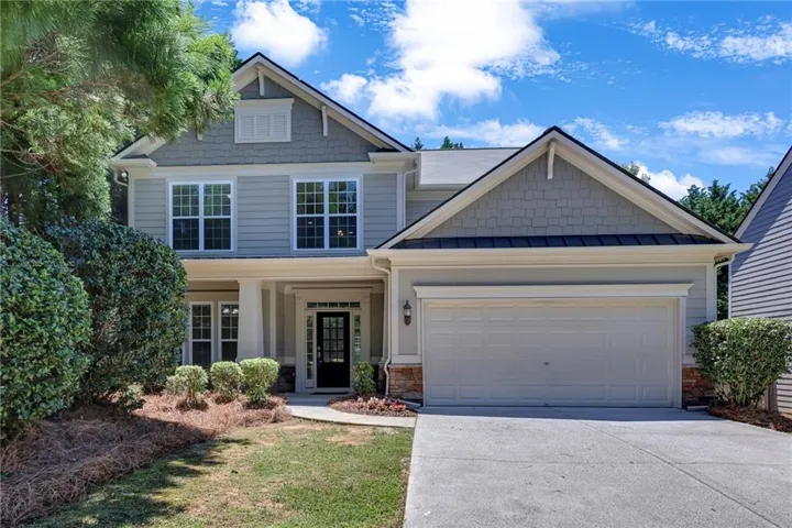 Two-story residence featuring light gray horizontal siding, an attached two-car garage, and a covered front entry