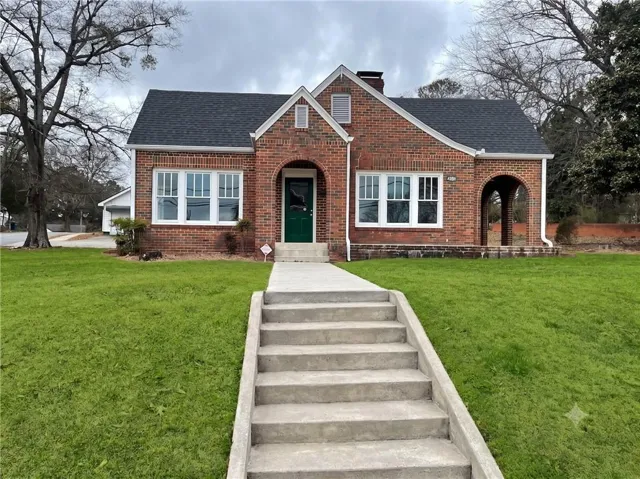 Brick exterior with a dark shingle roof, arched entryway, and multiple pane windows