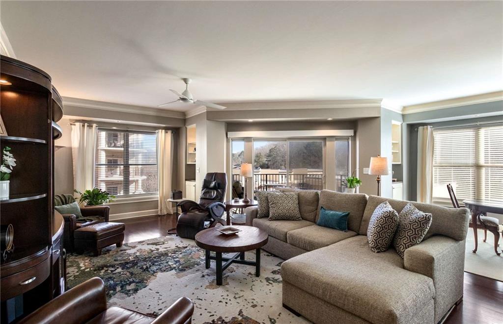 Throughout the living area and primary bedroom notice the beautiful rich hardwoods and crown molding detail.  Electric shade with remote for sliding glass door is such a wonderful asset to the room.  You can't believe how spacious the living room/dining room/ and kitchen area feel.