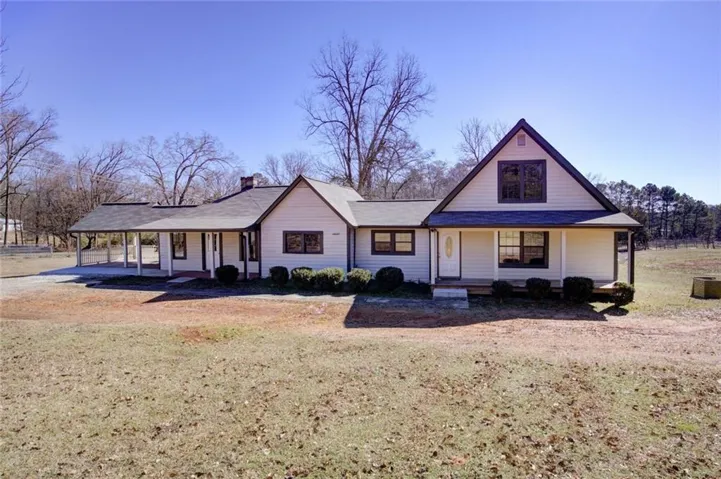 View of front of property with covered porch, an attached carport, a chimney, and a front lawn