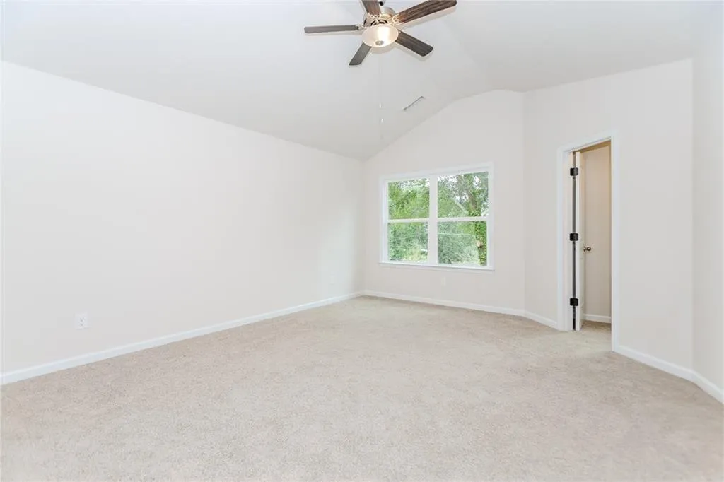 Spare room with light carpet, vaulted ceiling, and ceiling fan