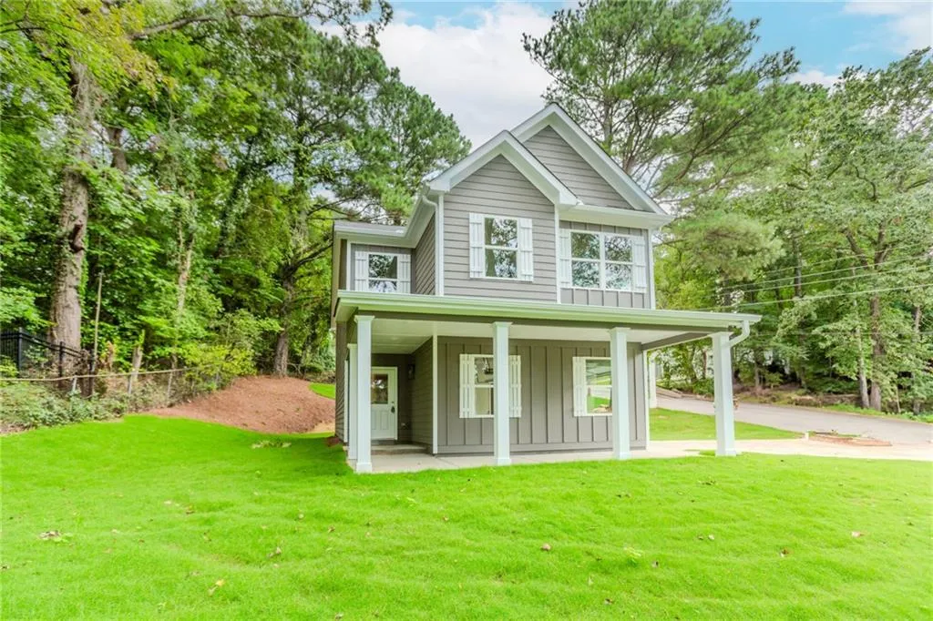 View of front of house featuring board and batten siding, covered porch, view of wooded area, and concrete driveway