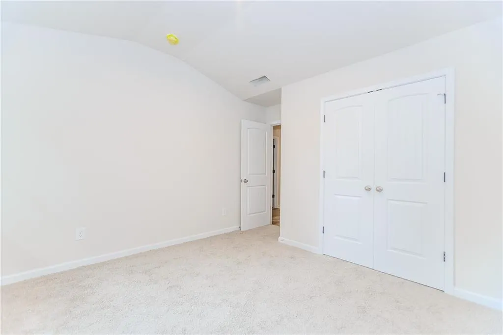 Unfurnished bedroom with lofted ceiling, carpet, and a closet