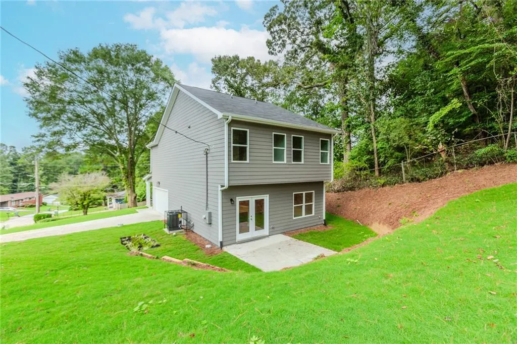 Rear view of house featuring concrete driveway, a patio, and a yard
