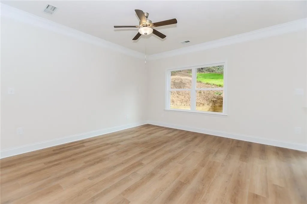 Spare room featuring ornamental molding, light wood-style floors, and ceiling fan