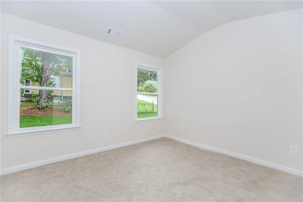Carpeted spare room with lofted ceiling and baseboards