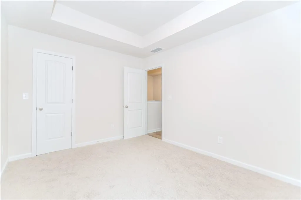 Unfurnished bedroom featuring carpet and a tray ceiling