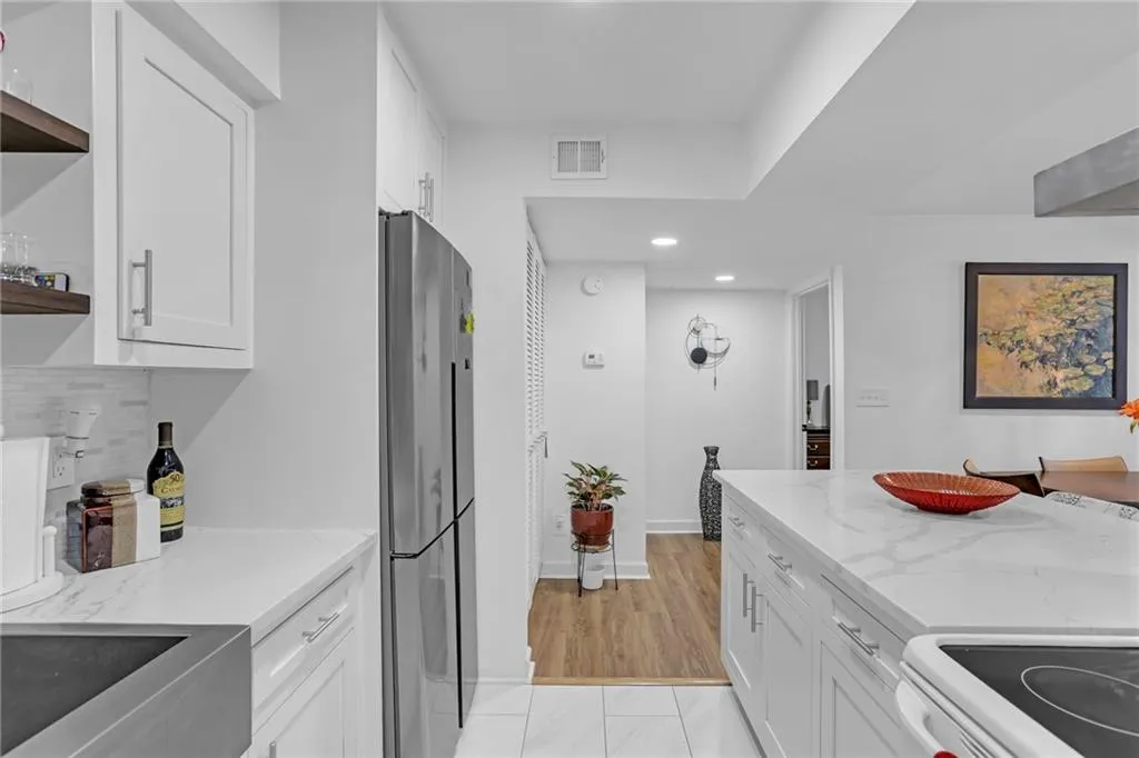 Kitchen with white cabinetry, open shelves, light stone counters, freestanding refrigerator, and white stove