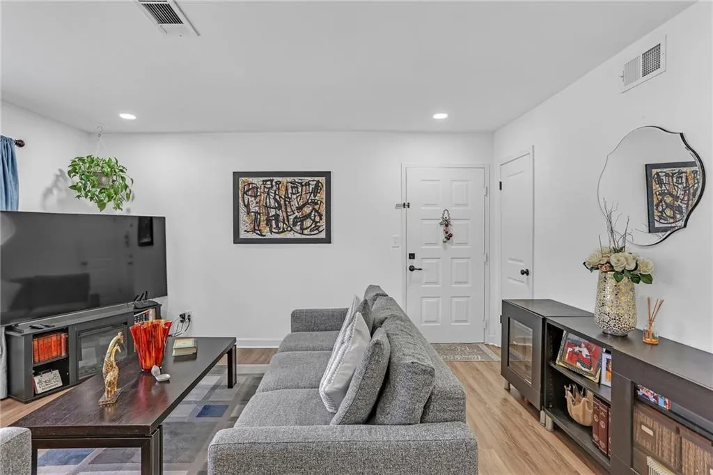Living area with light wood-type flooring and recessed lighting