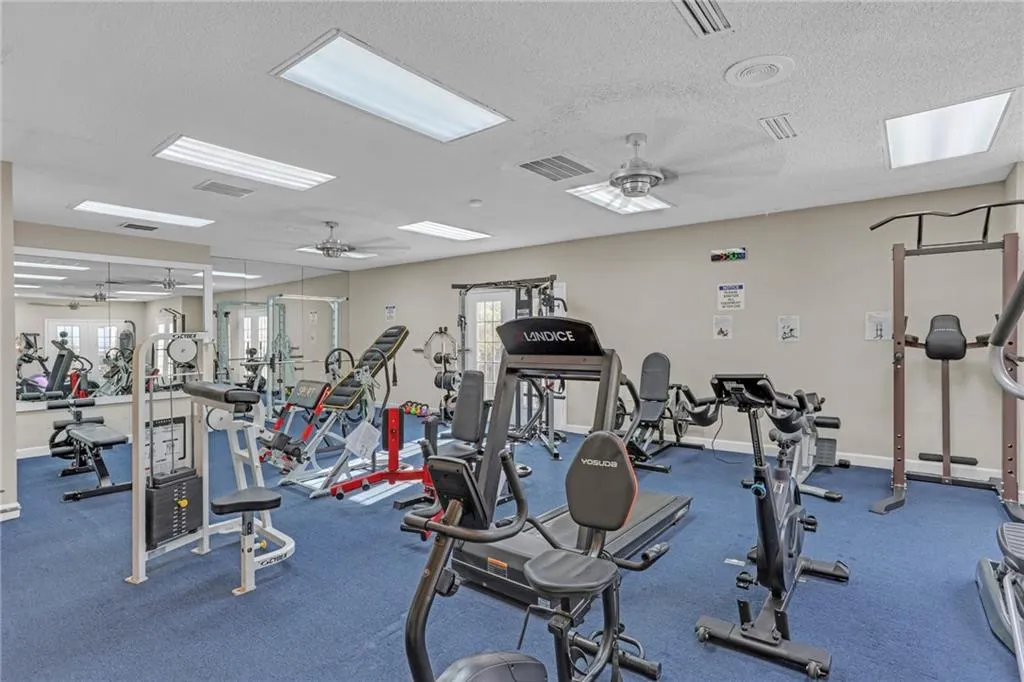 Exercise room with a ceiling fan and a textured ceiling