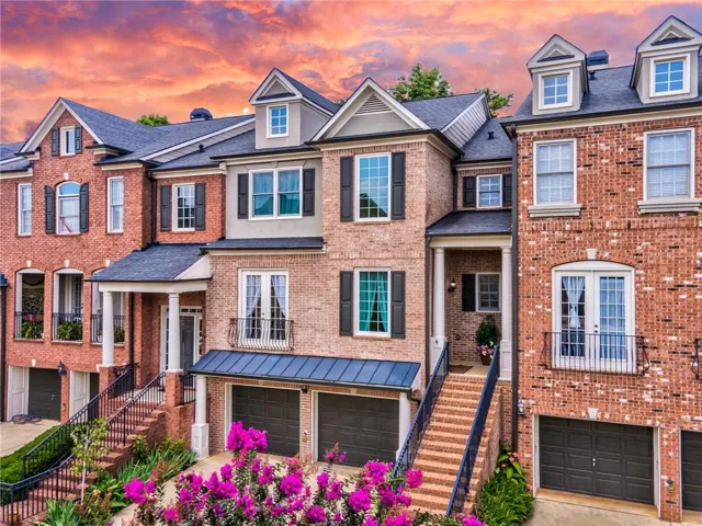 Brick exterior with multiple dormers, covered entry, and individual garages