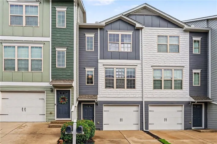 Multi-level facade featuring varied siding textures, multiple window configurations, and integrated garages with overhead doors