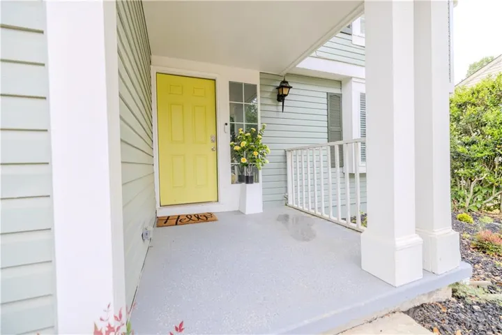 Covered porch entrance featuring a vibrant yellow door, complementary light blue siding, and white architectural columns