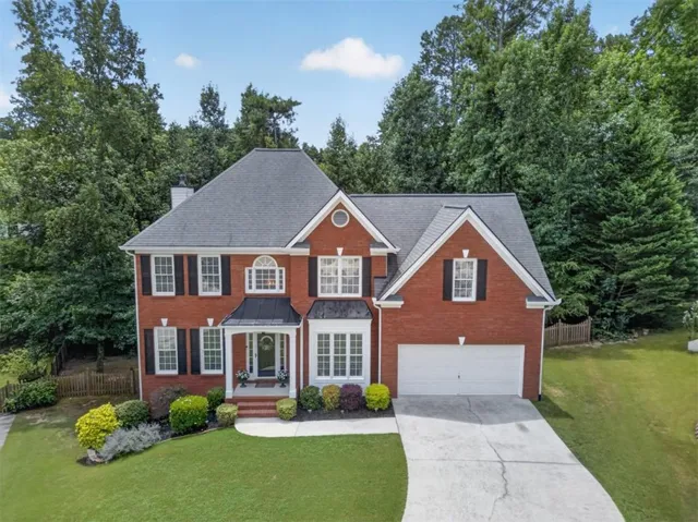 Two-story brick exterior featuring a multi-gabled roofline and black shutters