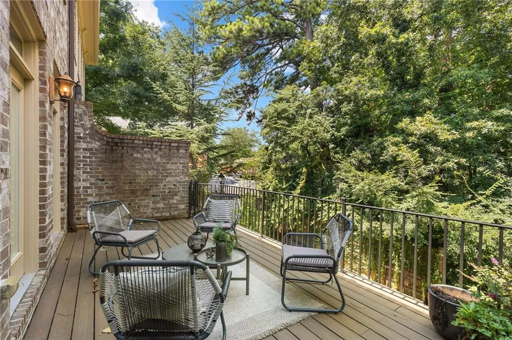Outdoor deck featuring wood-finish flooring, a brick exterior wall, and a black wrought iron railing