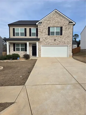 Two-story residence featuring light brick masonry and dark shingle roofing