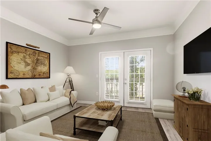 Living area featuring wood-finish flooring, a contemporary ceiling fan, and crown molding