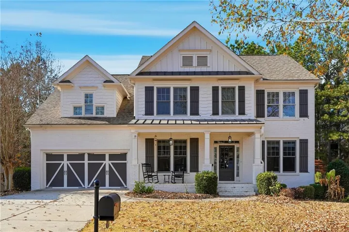 View of front of house featuring board and batten siding, covered porch, brick siding, and driveway