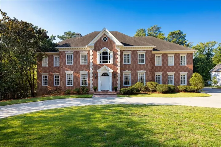 Brick exterior with white trim, arched dormer window, and a white front door
