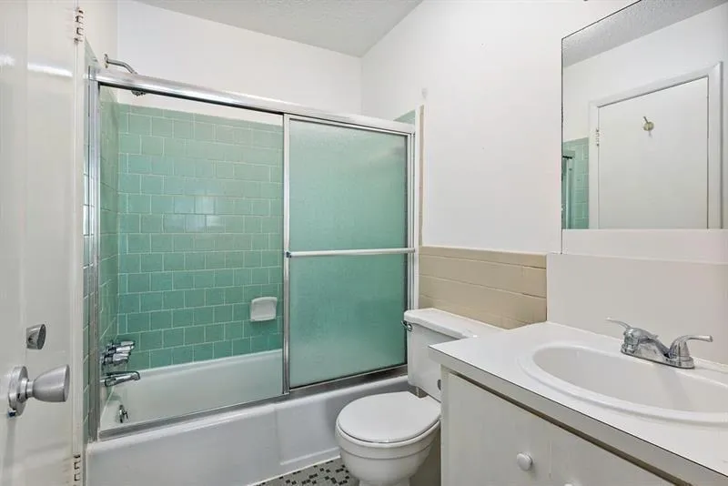 Full bath featuring vanity, shower / bath combination with glass door and tiled floors.