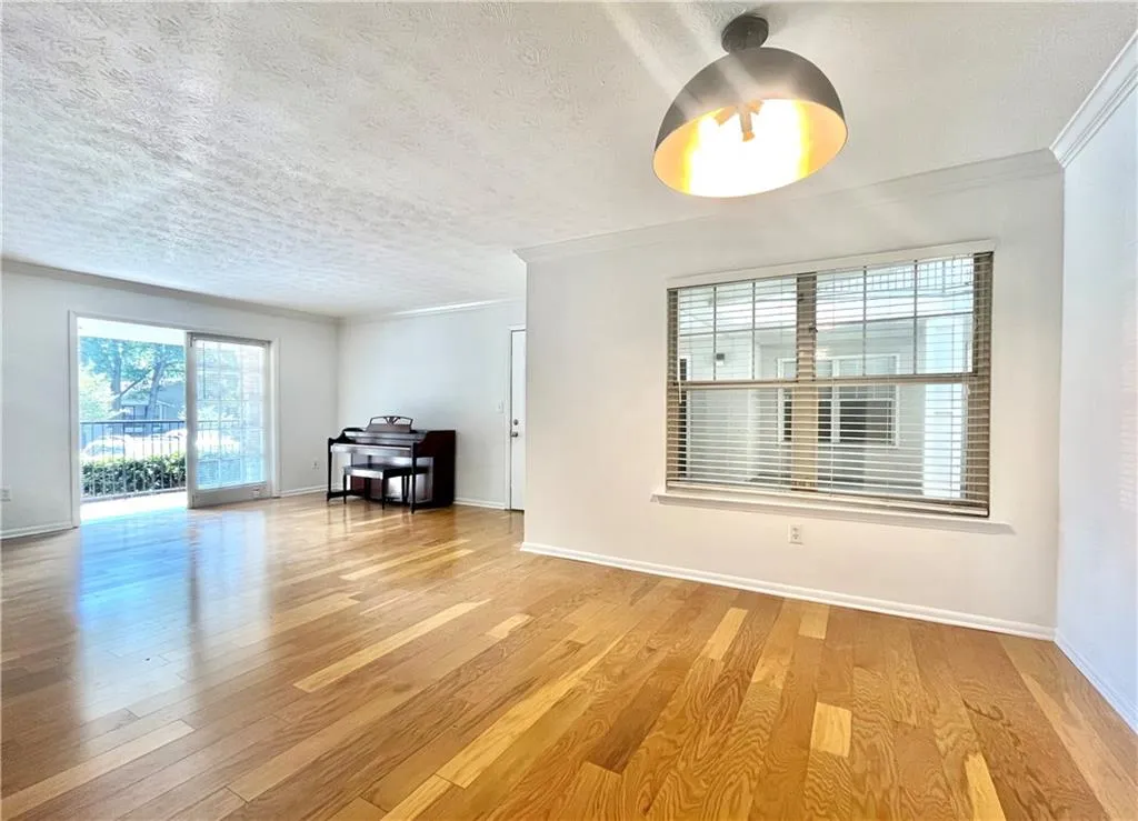 Unfurnished living room with crown molding, plenty of natural light, light wood-style floors, and a textured ceiling