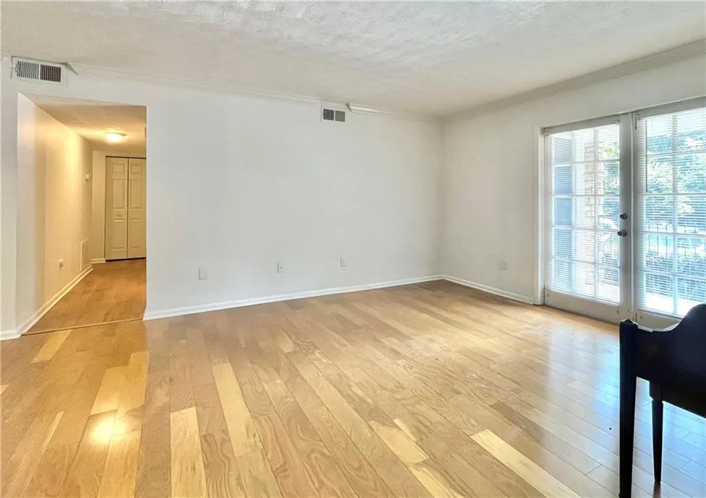Spare room with a textured ceiling, light wood-style flooring, crown molding, and french doors
