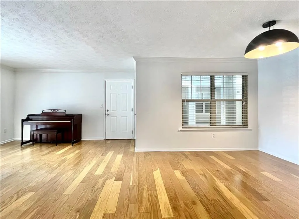 Living room featuring a textured ceiling, light wood-style floors, and ornamental molding