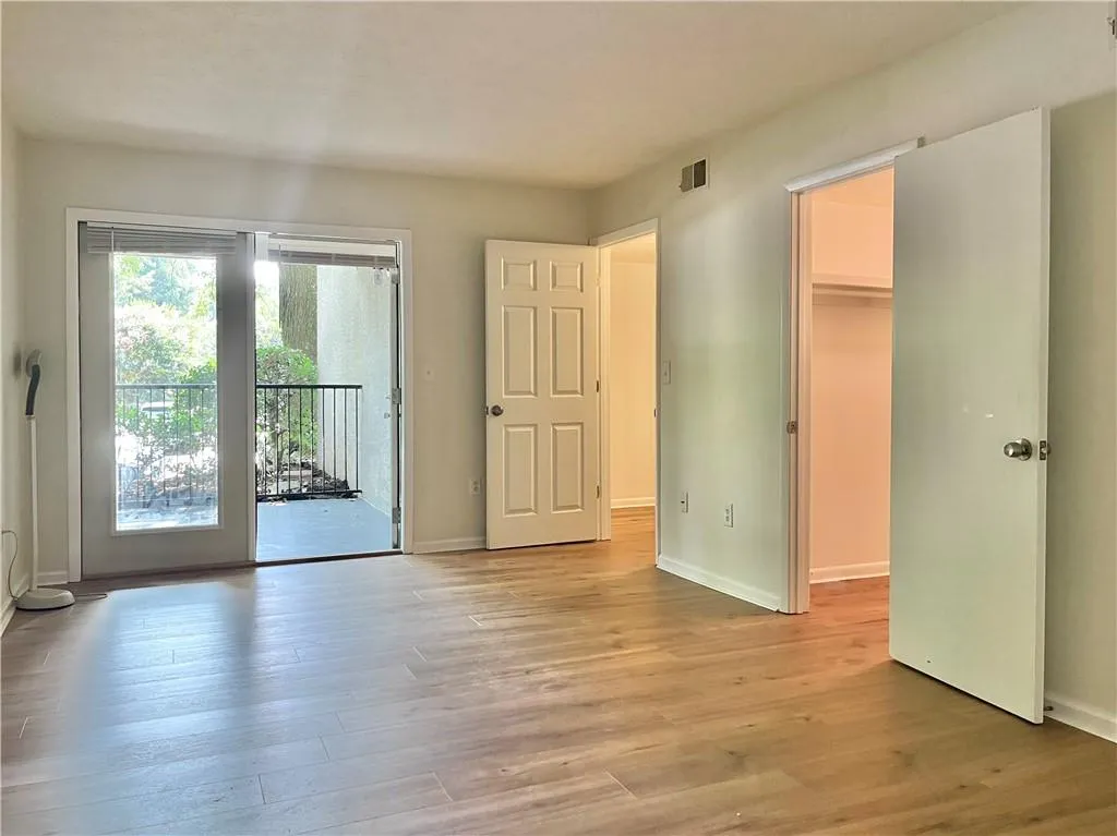 Unfurnished bedroom with light wood finished floors, a walk in closet, and access to exterior